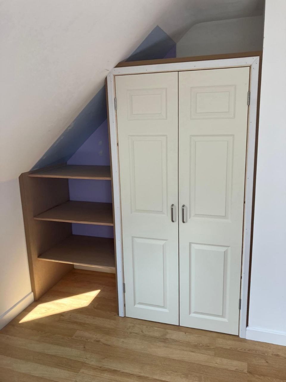 Built-in storage cupboard and open shelving fitted into the space under a staircase