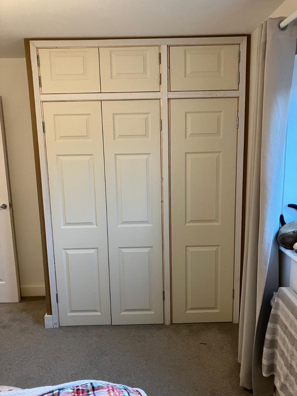 Fitted wardrobe with six panel doors and matching cupboards built in above