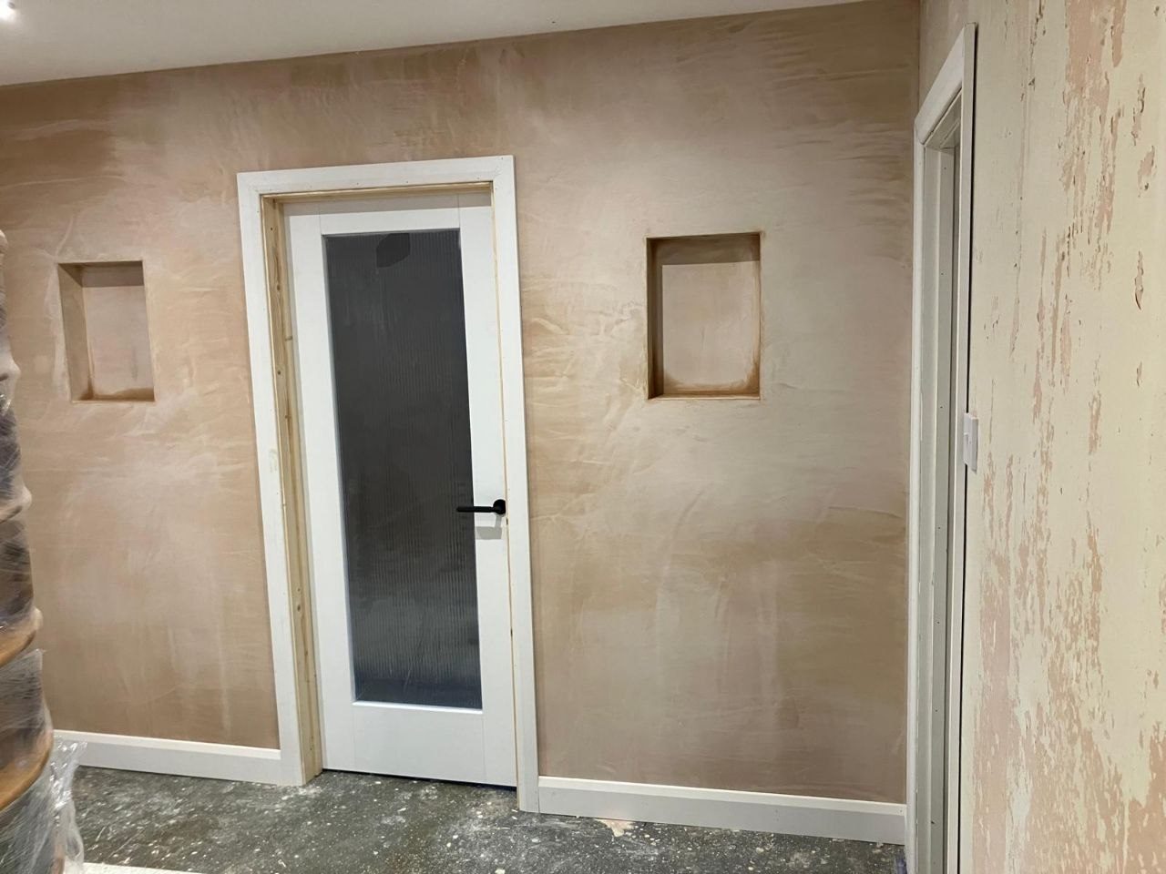 Plastered timber stud partition wall with a glazed door and two built-in shelf recesses