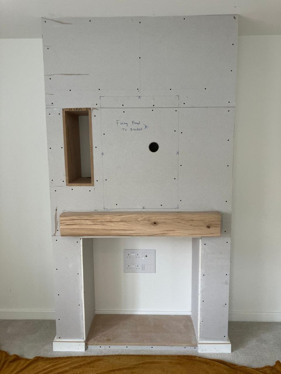 Faux chimney breast built in stud and board with a solid oak beam mantel and a recess for a fire