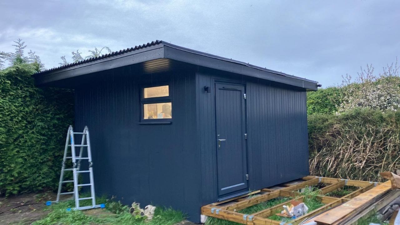 Garden studio clad in dark grey uPVC boarding with a matching door and fascia
