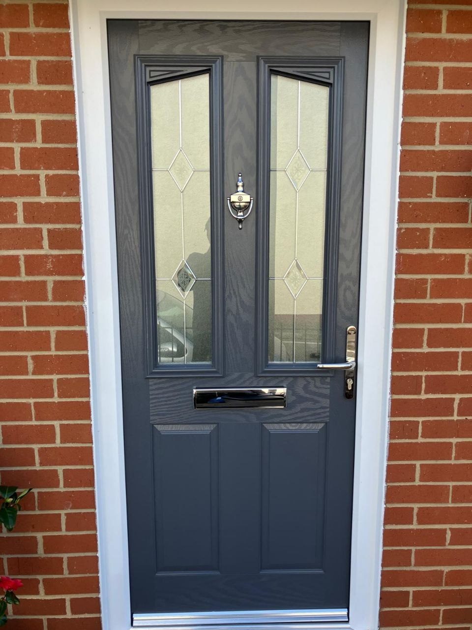 Anthracite composite front door with leaded glass panels, chrome furniture and a letterplate, fitted into a brick opening